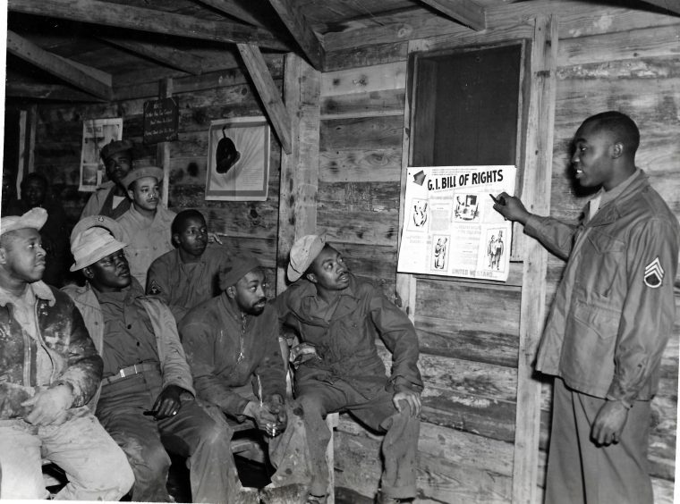 Staff Sergeant Herbert Ellison explaining the G.I. Bill to fellow soldiers Robert T. Walton, Tonil Carter, Lawrence Keys, Sam Anderson, James Millhouse, and James West of the 15th Air Force Service Command in Italy, 1944. Image via Library of Congress.