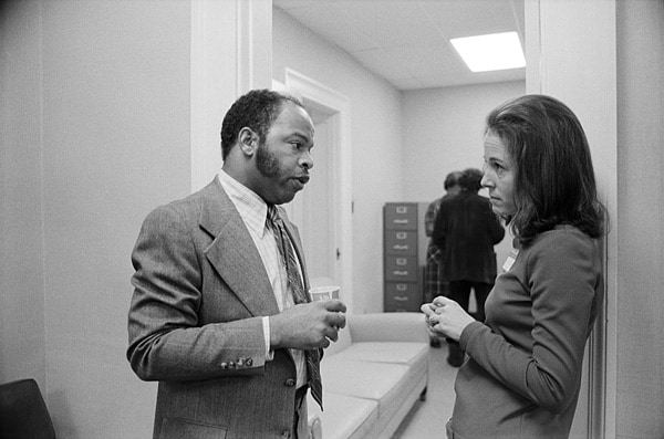 View of John Lewis, head of the Voter Education Project, and Carol Muldawer, staff member for Congressman Andrew Young, in conversation, ca. 1973.
