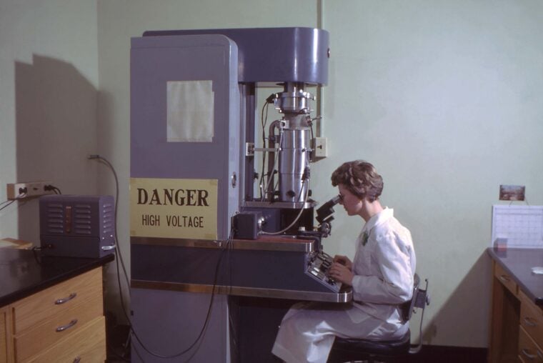 CDC electron microscopist looks under transmission electron microscope