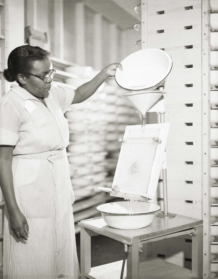 woman pouring a substance through a funnel