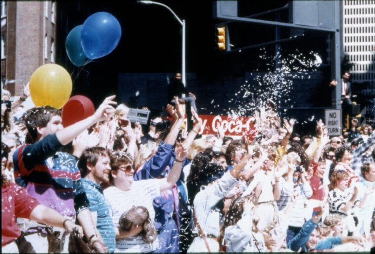 Crowd of people cheering with confetti and balloons
