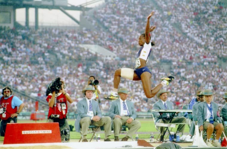 Woman jumping in front of spectators and cameramen on a track