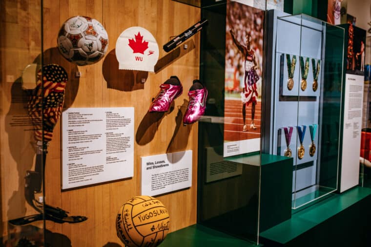 Image of various sports Olympic donations including purple track shoes, a soccer ball, a swim cap, a basketball