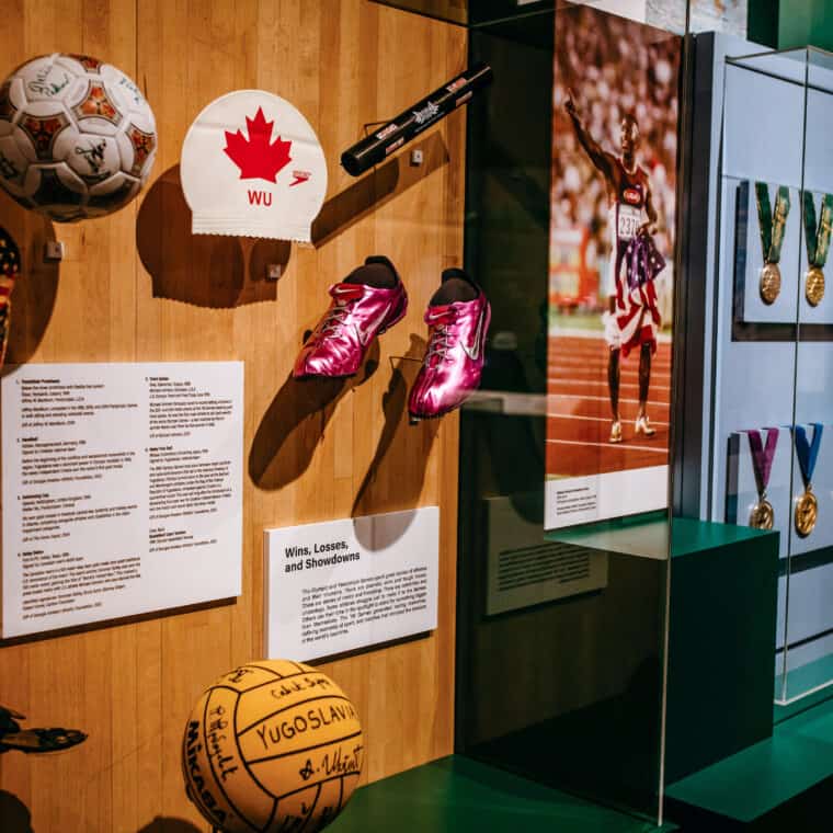 Image of various sports Olympic donations including purple track shoes, a soccer ball, a swim cap, a basketball