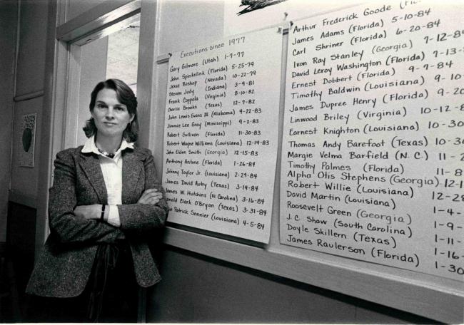 Murphy Davis standing in front of a list of executions that have taken place in the U.S. since 1977