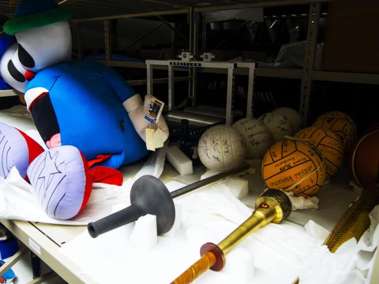 Archival shelves with volleyballs, torches, and stuffed animals