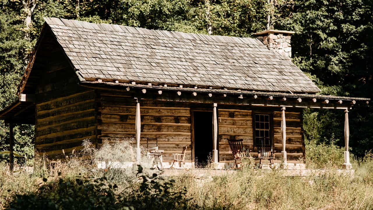 wood cabin with wooden rocking chairs on porch Zoom image