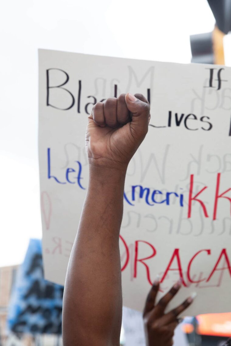 Raised arm at protest in front of Black Lives Matter poster