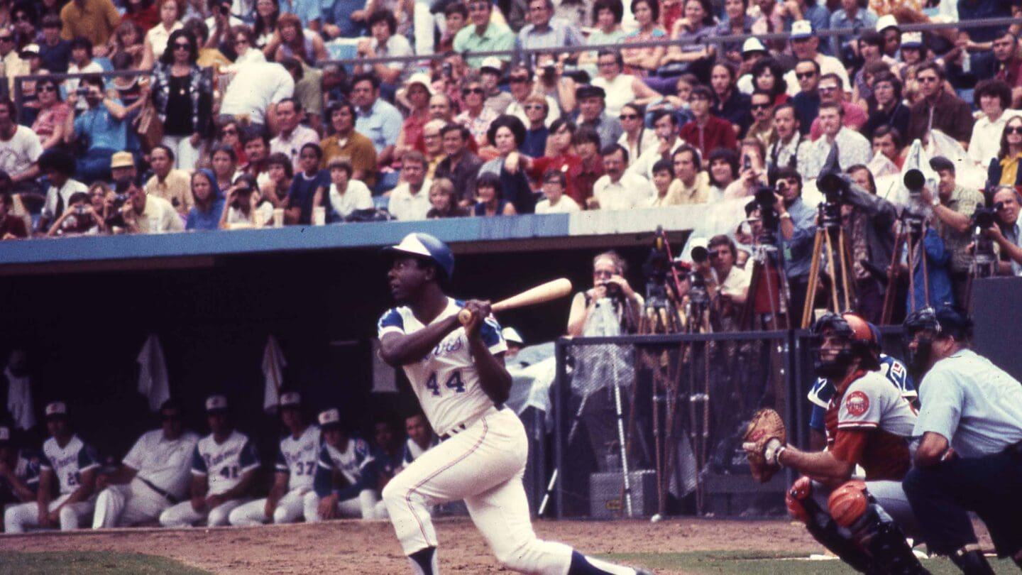 Photograph of Hank Aaron in blue and white Atlanta Braves uniform with fans in stands