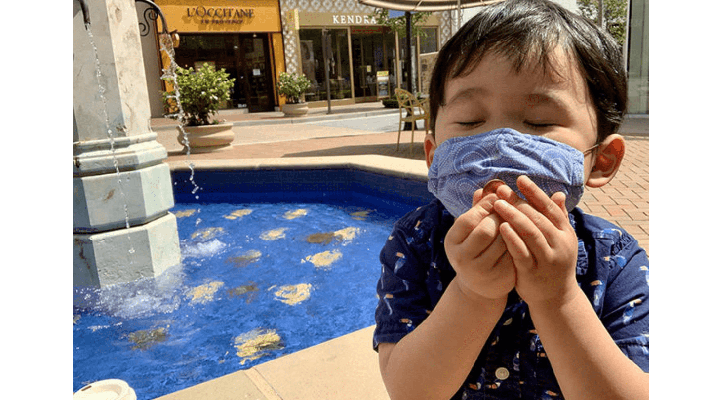 small boy wearing mask makes wish on a penny