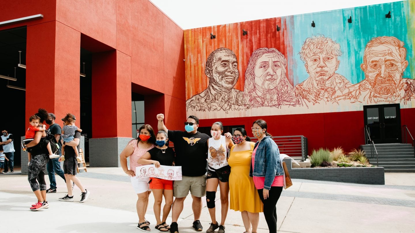 4 women smiling in front of mural
