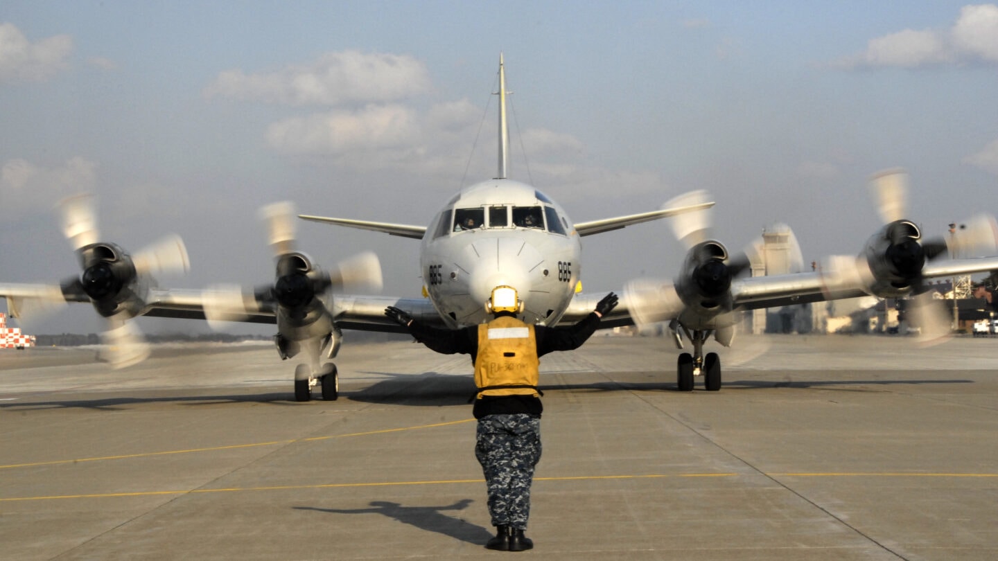 Navy airman signals the pilots of a P-3 Orion aircraft