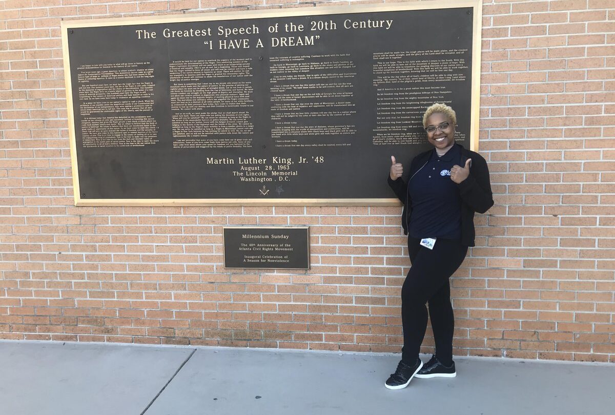 An Americorps VISTA worker poses in front of the Millenium Sunday plaque