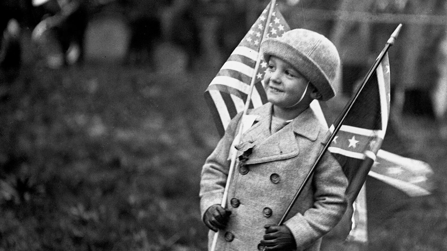A boy holding American and Confederate flag