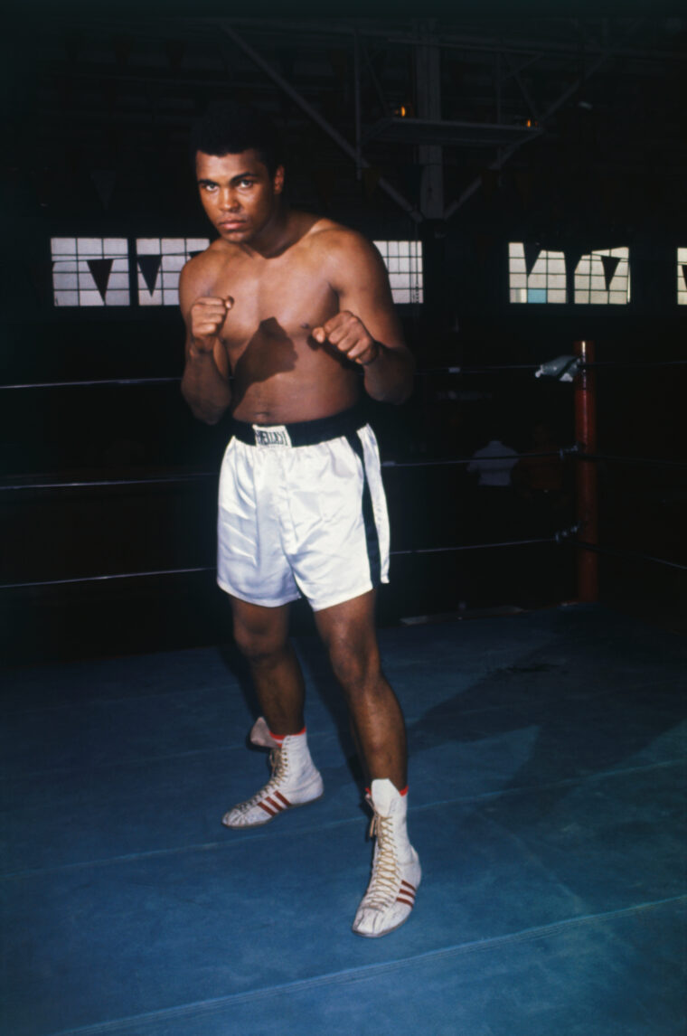 Muhammad Ali is shown in a boxing ring training for a fight with Jerry Quarry, wearing boxing shorts and with his hands in fists