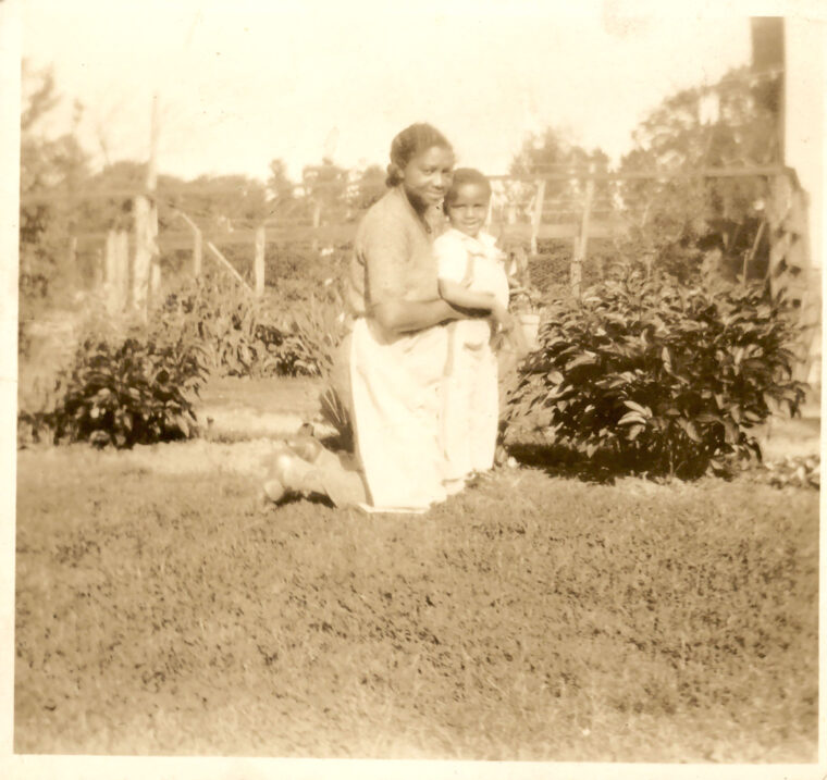 "Aunt Margaret and Ralph in the garden," with possibly peonies and iris, wire fence, posts, and lawn, circa 1930s