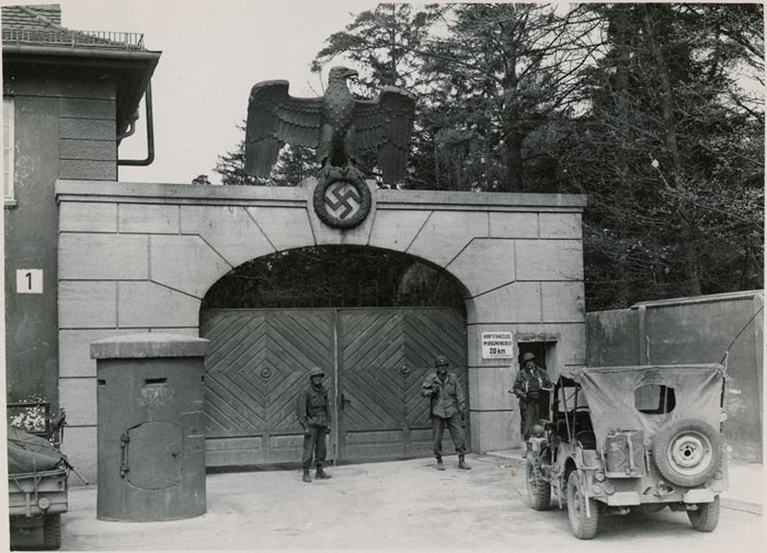 U.S Army soldiers guard the gates in front of the main entrance to the Dachau concentration camp, 1945