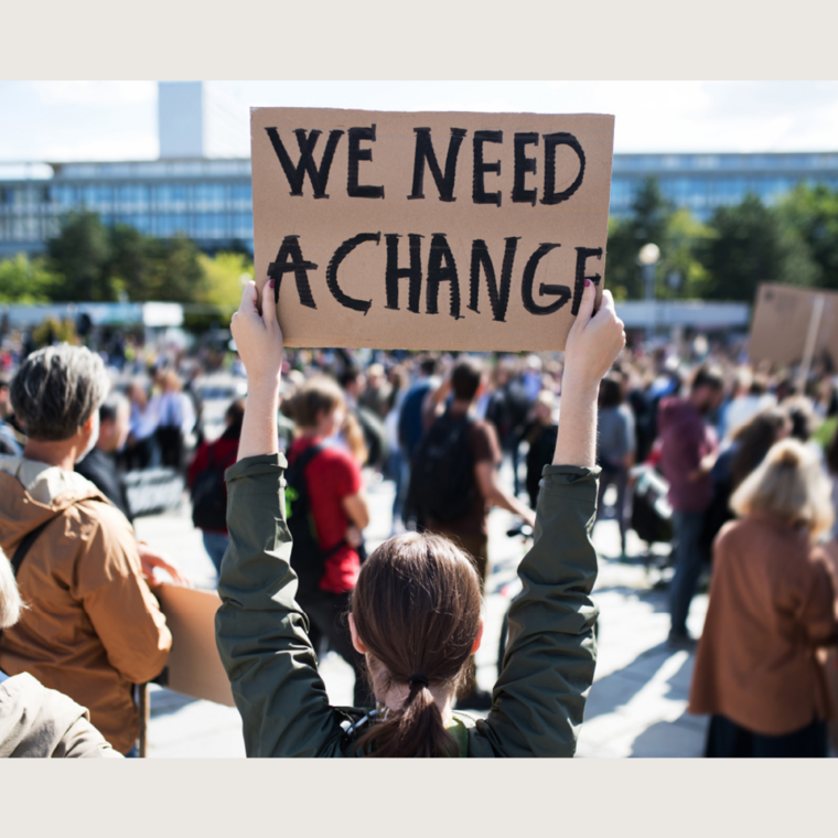 person holding sign that says "we need a change"