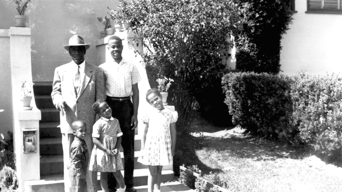 Family of five standing before steps of a house or building