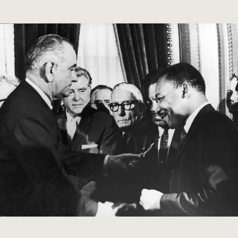 President Lyndon B. Johnson hands a pen to Dr. Martin Luther King Jr. at the signing of the Voting Rights Act
