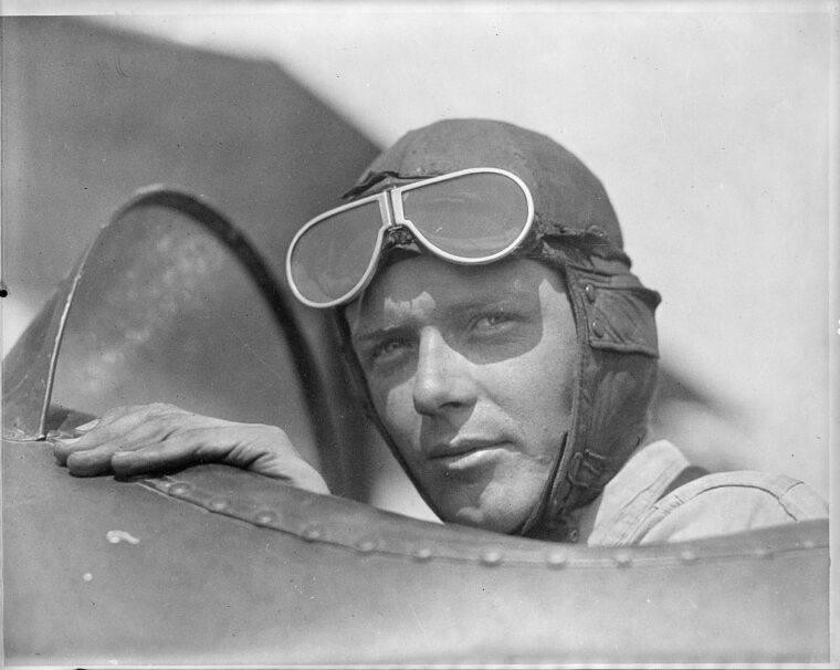 Charles Lindbergh, wearing helmet with goggles up, in open cockpit of airplane